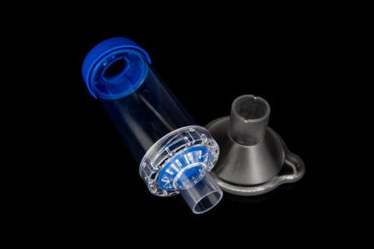 Transparent plastic medical inhaler spacer and face mask on black background