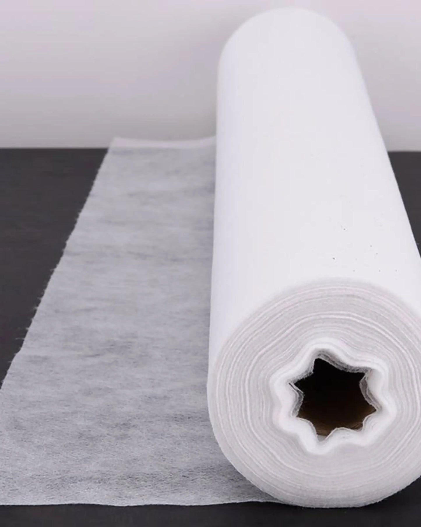 White disposable bed sheet roll for medical or spa use on dark surface