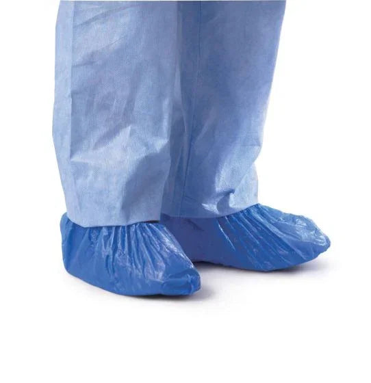 Person wearing disposable blue shoe covers over medical scrubs on white background