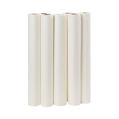 Six rolls of white medical examination table paper standing upright on a white background