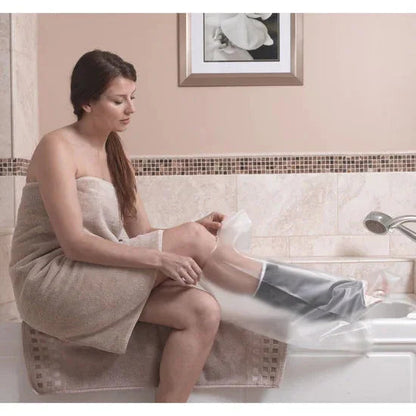 Woman in towel covering leg cast with waterproof foot protector in bathroom
