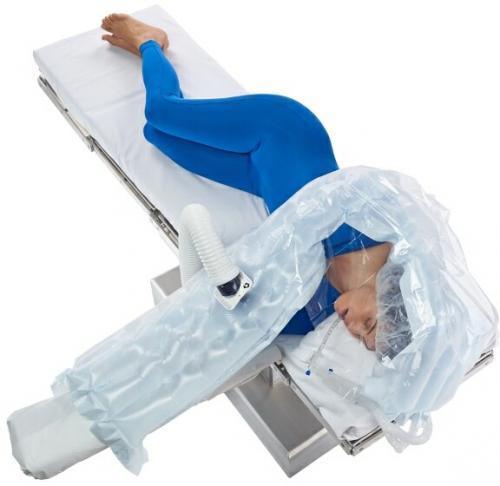 Person on medical table covered with upper body warming blanket for temperature management