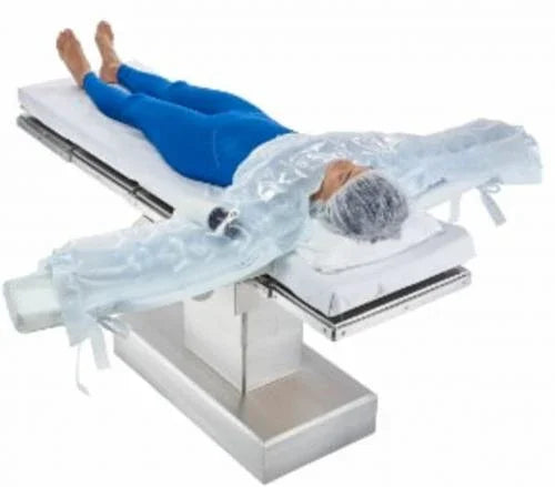Patient lying on surgical table covered with upper body warming blanket for temperature management