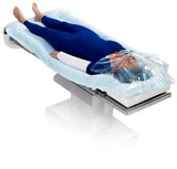 Patient on hospital bed covered with full-body warming blanket for medical temperature management