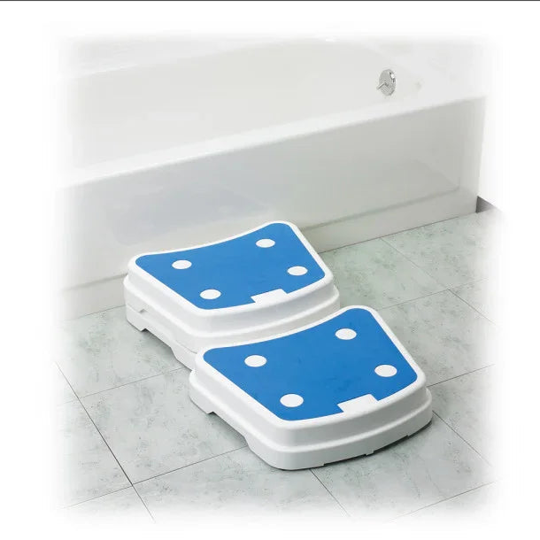 Stackable bath safety steps with blue non-slip surfaces beside a bathtub on tiled floor