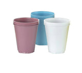 Stacked disposable plastic cups in pink, blue, and white for medical or home care use