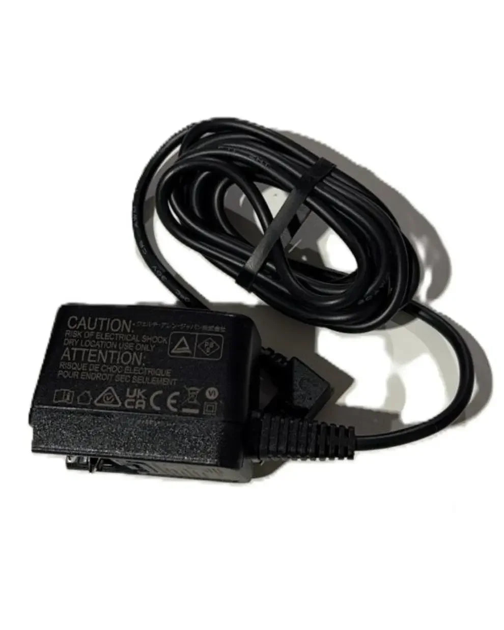 Black medical device power adapter with coiled cable on white background