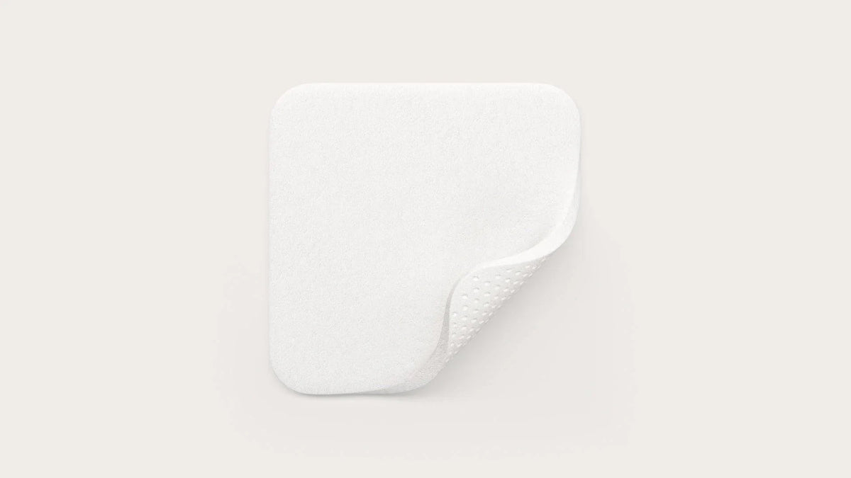 Square white medical absorbent pad with textured backing, shown on a clean background.