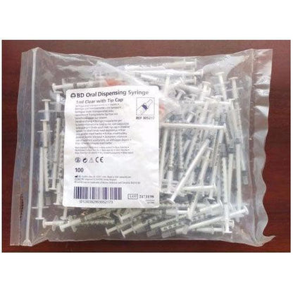 Bulk pack of 1ml BD oral dispensing syringes with tip caps for medical use on a table