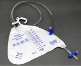 Disposable urinary drainage bag with measurement markings and attached tubing on gray surface