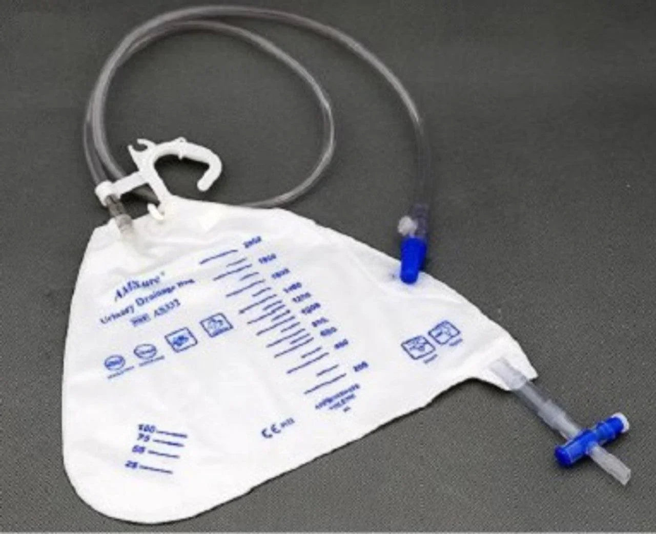 Disposable urinary drainage bag with measurement markings and attached tubing on gray surface
