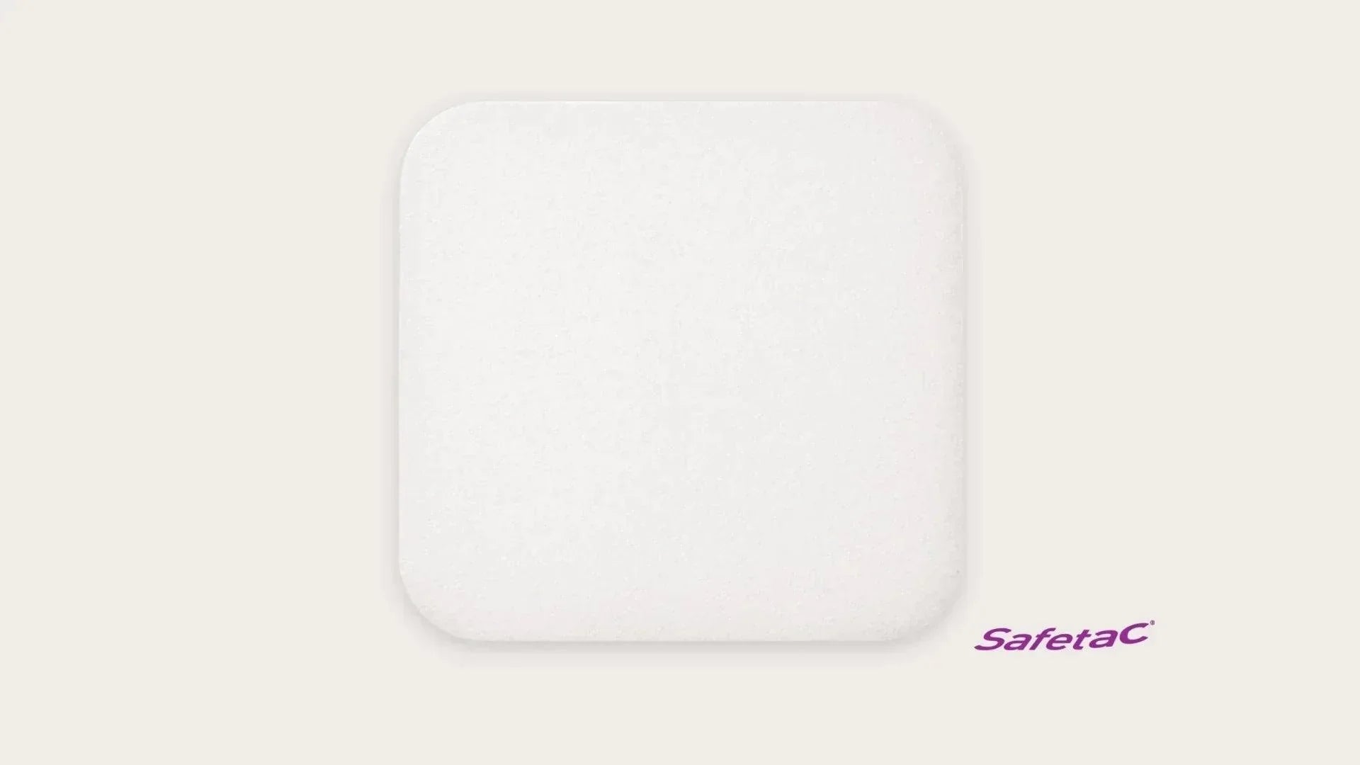 Square white foam wound dressing with rounded corners, Safetac medical pad on light background