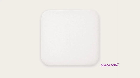 Square white medical wound dressing pad with rounded corners, plain background, Safetac logo