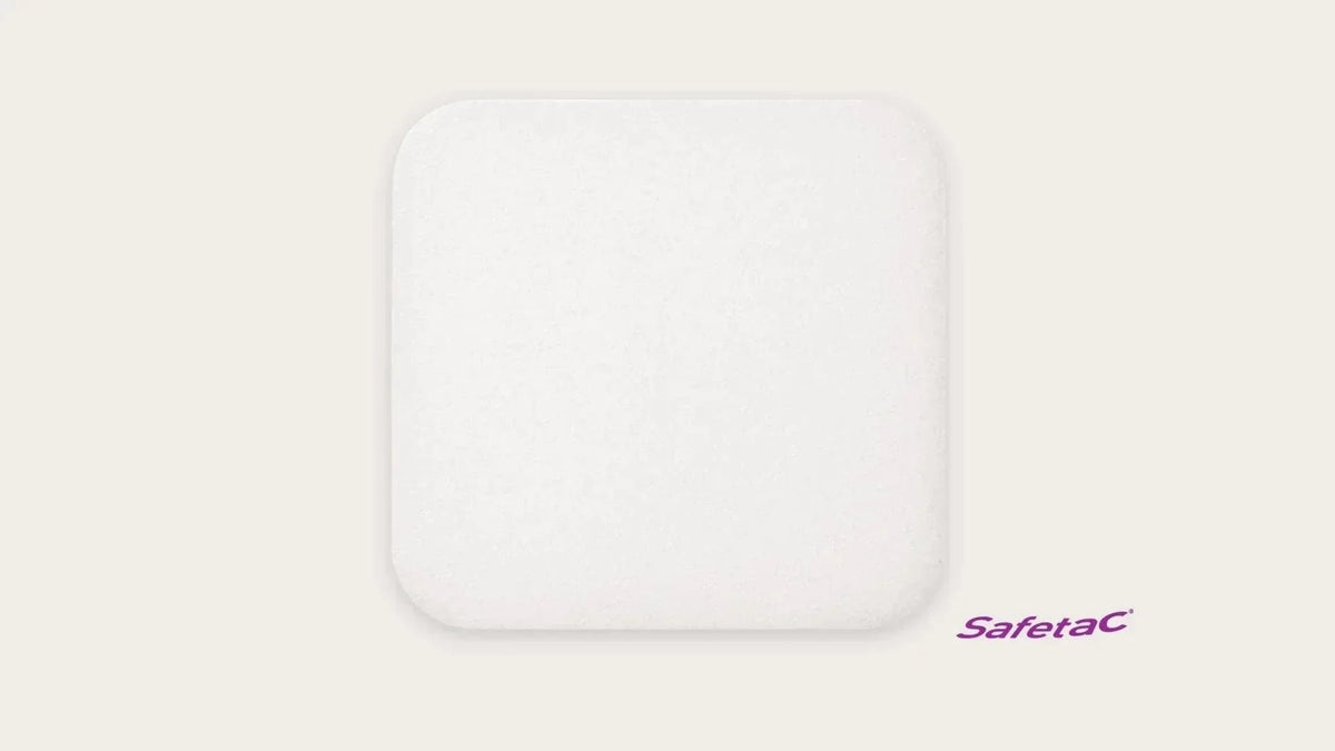 Square white medical foam dressing pad with rounded edges and Safetac logo on light background