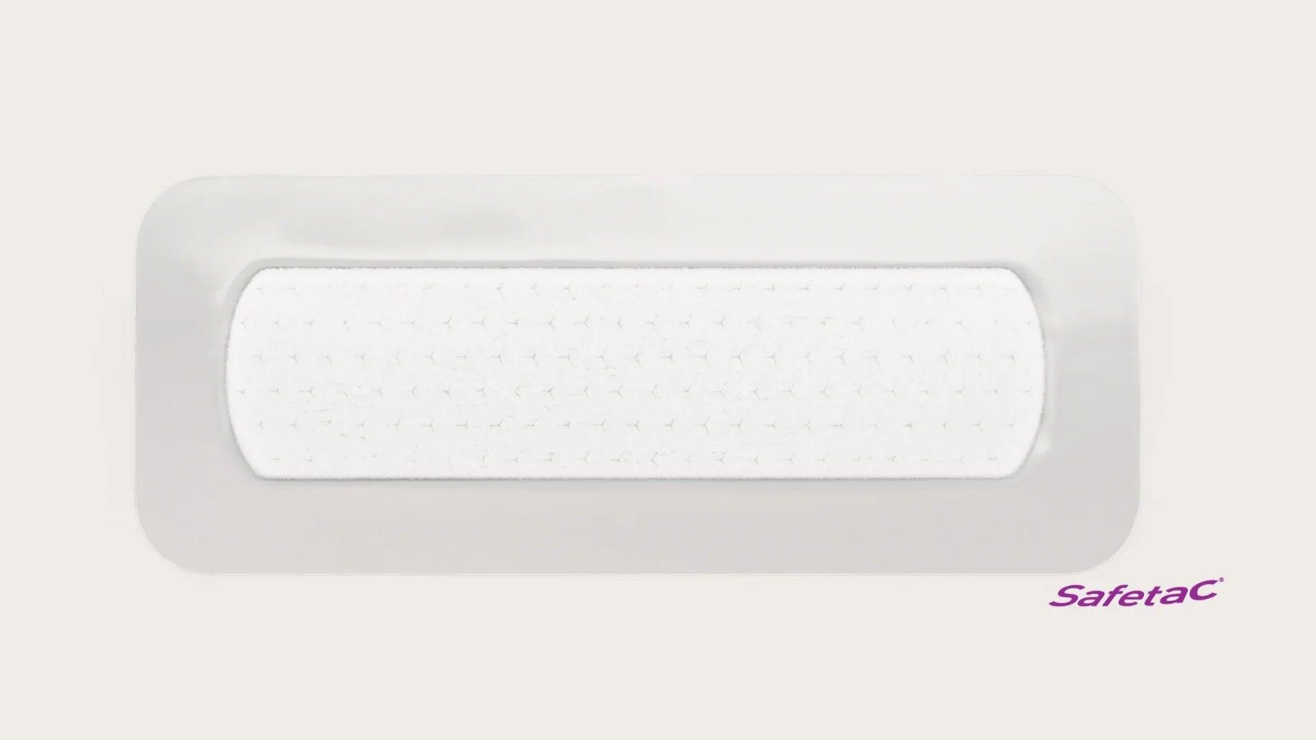 Rectangle adhesive wound dressing with white absorbent pad and Safetac logo on plain background