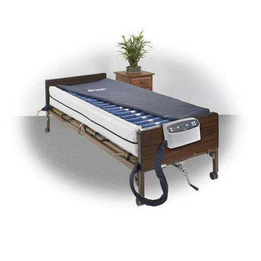 Hospital bed with adjustable air mattress, medical equipment, and wooden bedside table