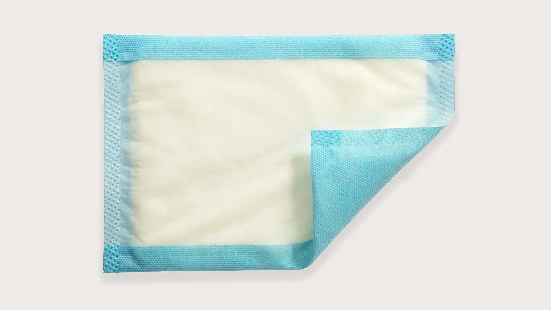 Disposable blue and white underpad for medical or incontinence care on white background