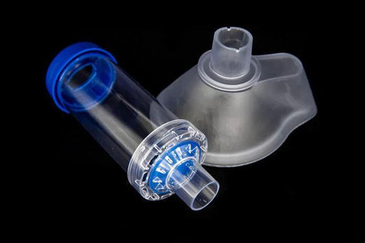 Spacer chamber and silicone face mask for inhaler, respiratory medical device on black background.