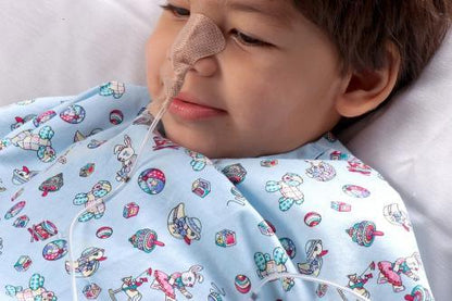 Child patient with nasal feeding tube wearing patterned hospital gown