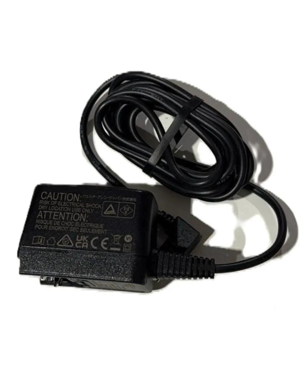 Black power adapter with coiled cable, medical equipment charger on white background