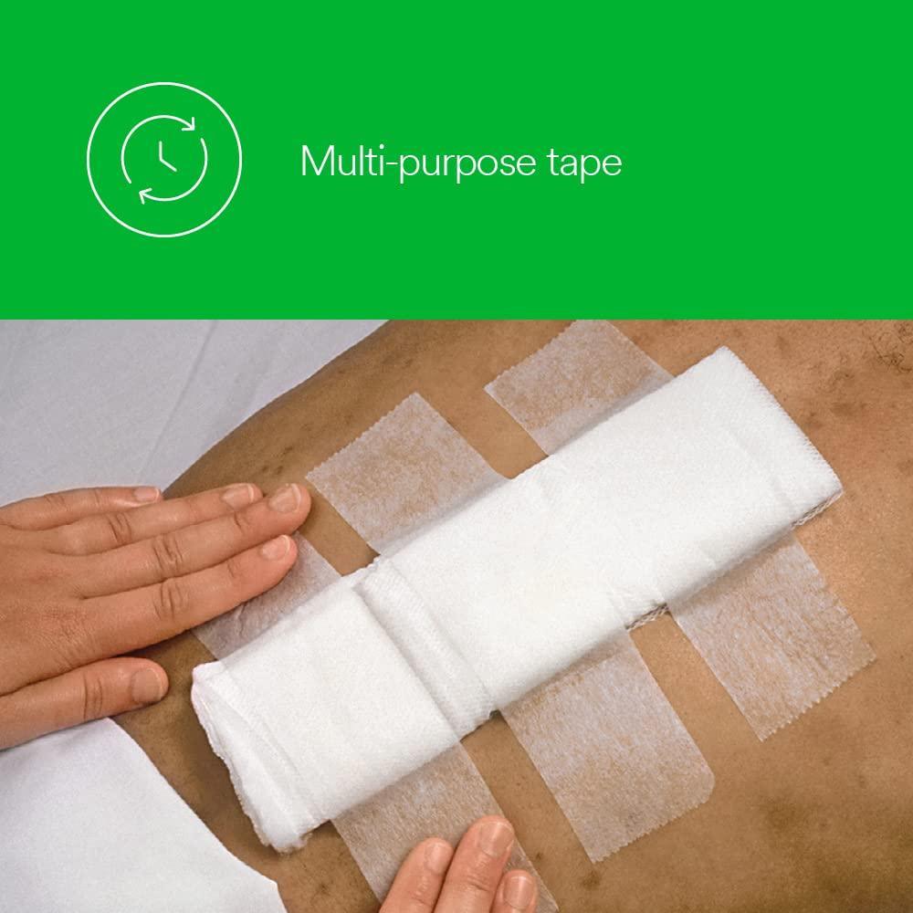 Medical paper surgical tape securing a large gauze pad on skin, hands applying tape, multi-purpose use