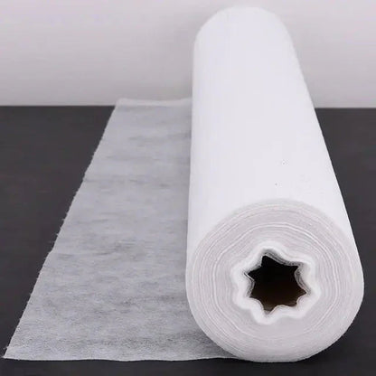 Medical disposable bed sheet roll unrolled on black surface for clinic or spa use