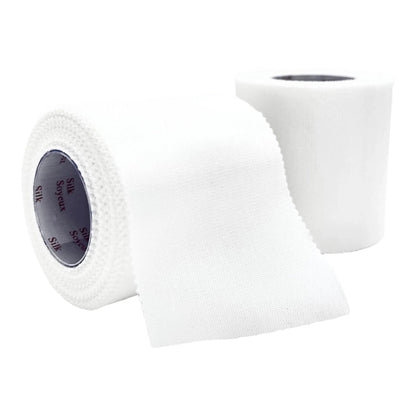 Two rolls of white medical silk tape, one partially unrolled, for wound care and bandaging