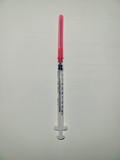 Medical syringe with measurement markings and pink safety cap on white background