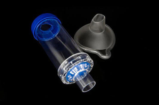 Clear plastic asthma spacer with blue cap and detachable mask on black background