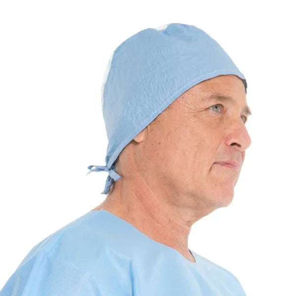 Man wearing a disposable blue surgical cap and medical gown, side profile view