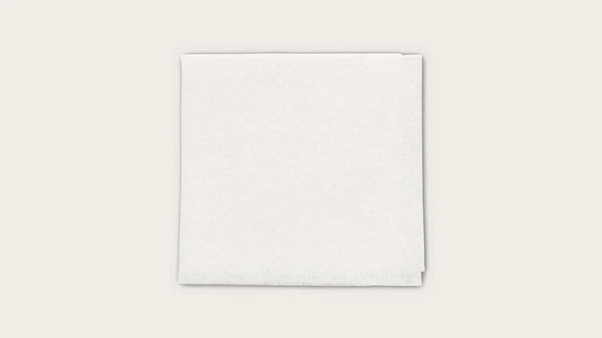 Stack of white sterile medical gauze pads on a plain background
