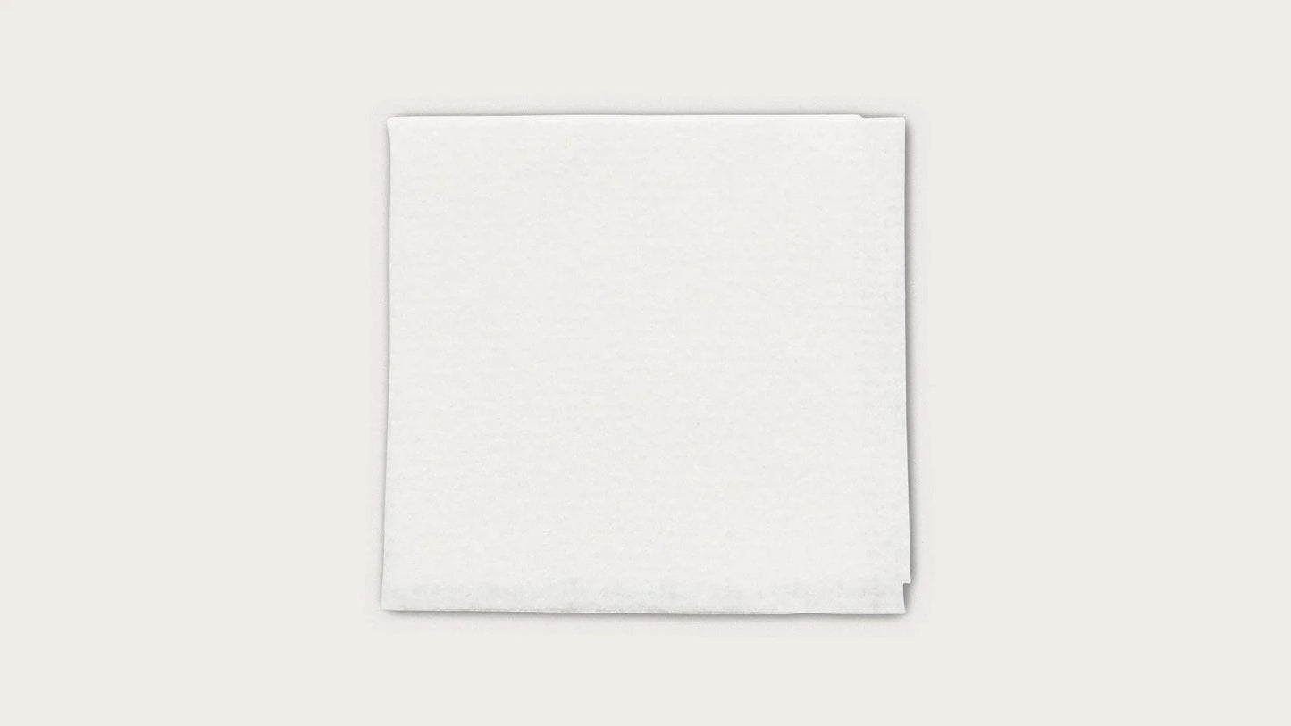 Stack of white disposable medical towels on a plain background