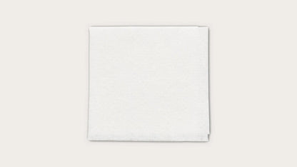 Stack of white disposable medical towels on a plain background