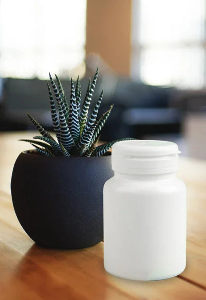 White medicine bottle on wooden table beside a small potted succulent, indoor setting