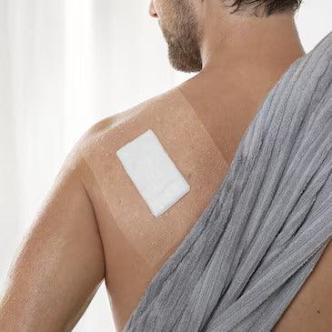 Transparent adhesive film dressing covering a bandage on a person's shoulder