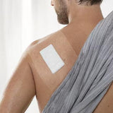 Transparent adhesive film dressing covering a bandage on a person's shoulder